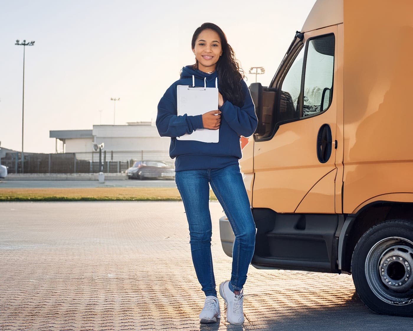 Conductrice souriante avec porte-documents devant un utilitaire, hub formations transport CFB Lyon